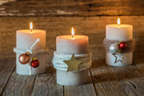 Three burning xmas candles with christmas decoration von Alex Winter
