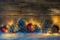 Weihnachtsdekoration mit Zapfen, Lichter und roten Weihnachtskugeln im Schnee by Alex Winter
