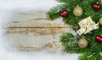 Klassische Weihnachtsdeko mit Tannenzweigen, Weihnachtsschmuck und Schnee-Rahmen auf Holz by Alex Winter