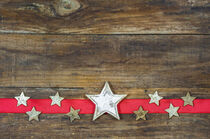 Christmas decoration with xmas stars on red ribbon and rustic wood by Alex Winter