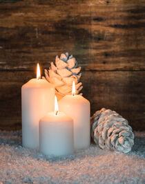 Three white candles with white pine cones for Christmas or Advent by Alex Winter