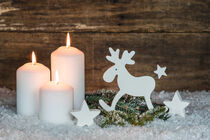 Weihnachtsdekoration mit drei brennenden Kerzen und Rentier im Schnee für Advent oder Weihnachten von Alex Winter