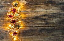 Red and golden christmas stars with lights border on rustic wood by Alex Winter