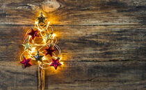 Christbaum aus roten und goldenen Sternen mit Lichterkette auf Holz by Alex Winter