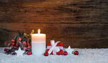 Kerze mit Weihnachtsgeschenk und Weihnachtsdekoration im Schnee by Alex Winter