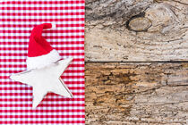 Rote Nikolausmütze auf Weihnachtsstern mit rustikalem Holzhintergrund von Alex Winter