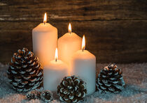 Christmas decoration with four white burning candles and pine cones by Alex Winter