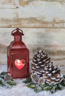 Rustic Christmas decoration with burning candle in red lantern on snow by Alex Winter