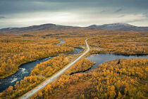 Lake, river, road and mountains with yellow trees in autumn along the scenic Wilderness Road in Lapland in Sweden from above by Bastian Linder