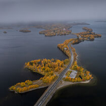 Road along islands and village of Saxnäs along Wilderness Road with trees in autumn in Lapland in Sweden from above by Bastian Linder