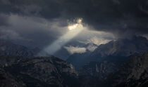 Sunbeams through dark clouds in the sky above Dolomite Alps mountains von Bastian Linder