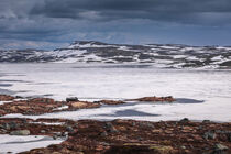 Hut at the waterfront of a frozen lake in the landscape of Hardangervidda National Park in Norway von Bastian Linder