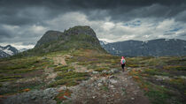 Woman hiking in mountain landscape to Knutshoe summit in Jotunheimen National Park in Norway by Bastian Linder