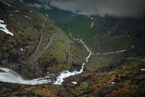 Mountain road Trollstigen winding through landscape with waterfall and valley of Trollveggen in Norway by Bastian Linder