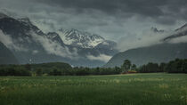 Landscape of Romsdalen with snowy mountains of Troll Wall in rain clouds and red cabin in Norway von Bastian Linder