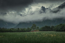 Landscape of Romsdalen with mountains of Troll Wall in rain clouds and red cabin in Norway by Bastian Linder