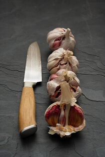 Stilleben, Knoblauchknollen in einer Reihe mit Küchemesser von Thomas Klee
