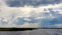 Sonnenstrahlen durchbrechen die dichten Gewitterwolken über Botswana