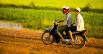 Girls Riding Along A Dirt Road In Cambodia. by Jason Friend