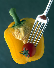 Close up of half yellow pepper with cherry tomato in center on fork tines by Panoramic Images