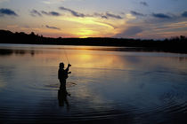 Fly-fisherman silhouetted by sunrise by Panoramic Images