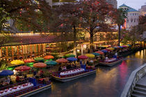 Restaurant along a river lit up at dusk by Panoramic Images