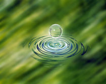 Clear bubble rising from ripples in mottled green water von Panoramic Images