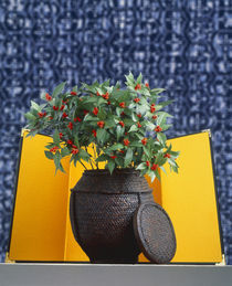 Gold screen with wooden vase and lid filled with small cherry tree on blue tweed von Panoramic Images