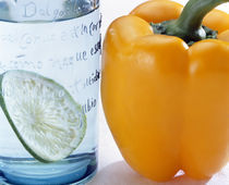 Close up of yellow pepper sitting beside blue glass with slice of lime by Panoramic Images