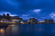 Buildings at the waterfront lit up at dusk by Panoramic Images