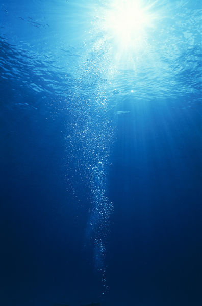 "Bright light shooting to surface of deep blue sea with trail of