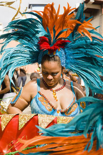 Woman in a turquoise feathered costume in the Port of Spain carnival in Trinidad. by Tom Hanslien