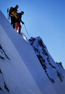 Skiers looking down a steep face. by Ross Woodhall