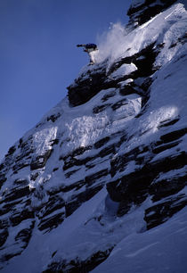 Snowboarder jumping off a cliff. by Ross Woodhall