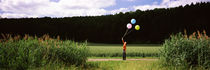 Woman holding balloons and standing in the field, Baden-Württemberg, Germany von Panoramic Images