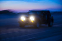 SUV riding off road at night. by John Greim