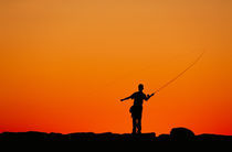 Boy fishing from a jetty. von John Greim