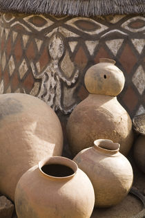 Handcrafted pottery leaning against traditional mud dwelling in Sirigu painted village von Danita Delimont