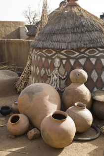 Handcrafted pottery leaning against traditional mud dwelling in Sirigu painted village by Danita Delimont