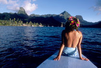 Woman enjoying view on bow of boat wearing flower garland by Danita Delimont