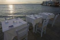 Three dinner tables overlooking the sea at sunset by Danita Delimont