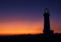 The sun ball drops down on the colorful horizon Yaquina Bay lighthouse on the coast near Newport by Danita Delimont