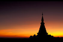 Sunset silhouette of Buddhist Chedi (temple) Phra Mahathat Naptha Methanidon by Danita Delimont