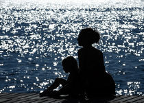 Profiles of mother and daughter against the glittering sea by Waldek Dabrowski