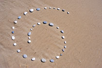 Pebbles arranged in spiral shape on beach von Sami Sarkis Photography