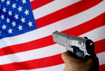 Man pointing gun on American flag von Sami Sarkis Photography