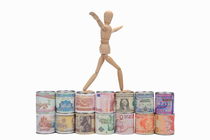 Wooden mannequin balancing on worldwide banknotes von Sami Sarkis Photography