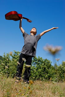Boy standing in meadow with guitar by Sami Sarkis Photography