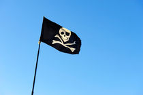 Skull and crossbones on Pirate's flag on blue sky by Sami Sarkis Photography