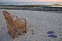 Wooden chair and slippers on beach at sunrise by Sami Sarkis Photography